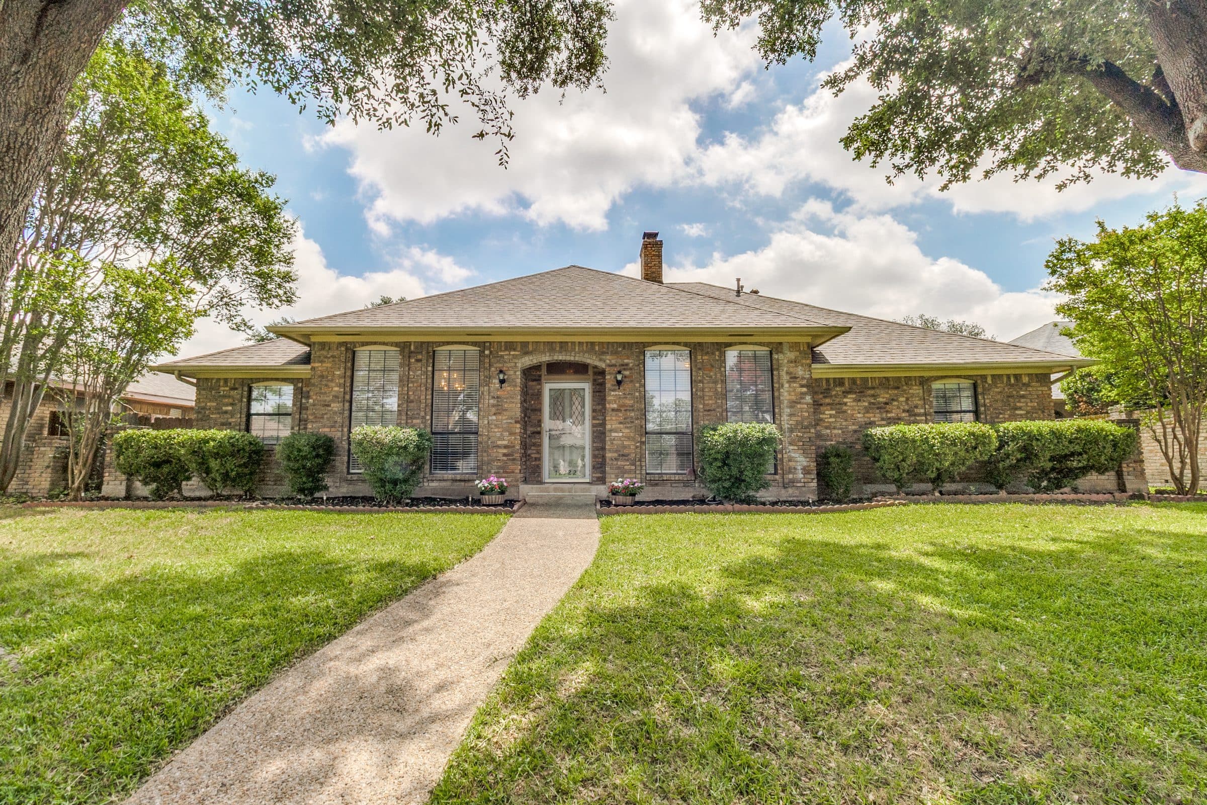 Traditional brick single-story home exterior with mature shade trees