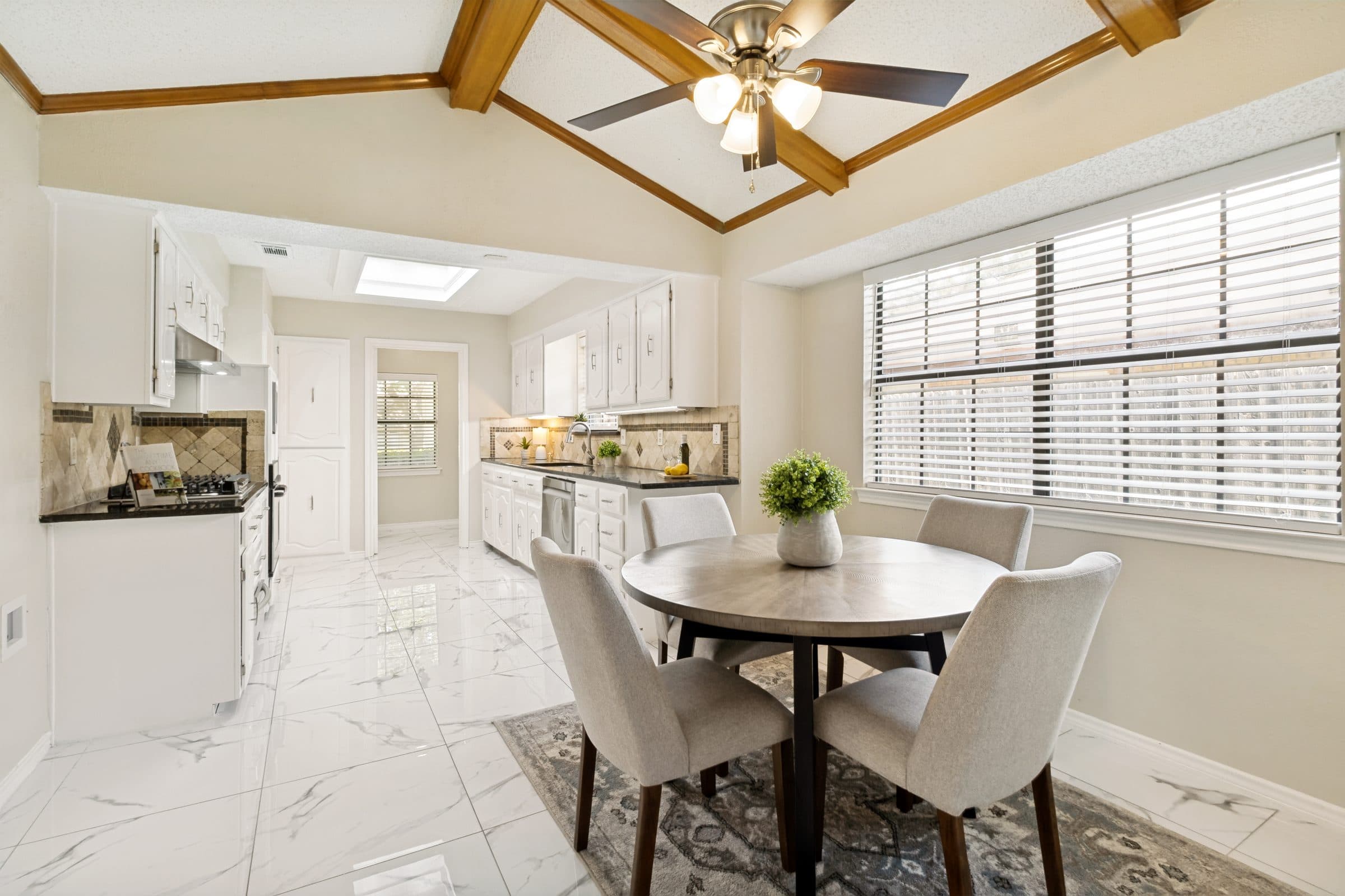 Bright kitchen and breakfast nook with marble-look tile flooring