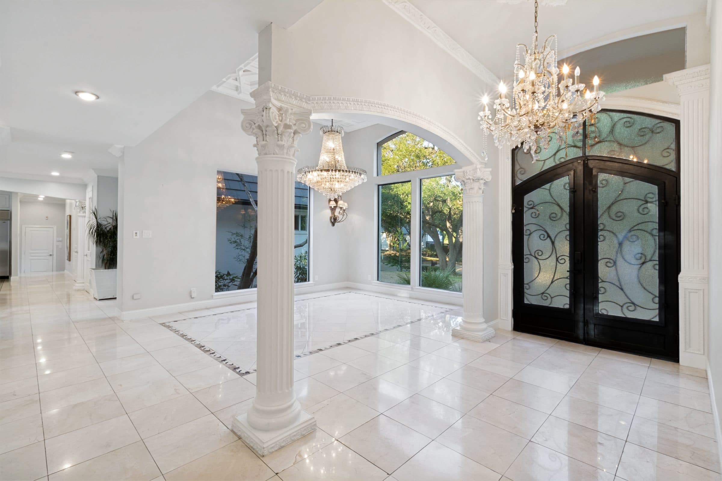 Grand entry foyer with marble flooring, columns and crystal chandeliers