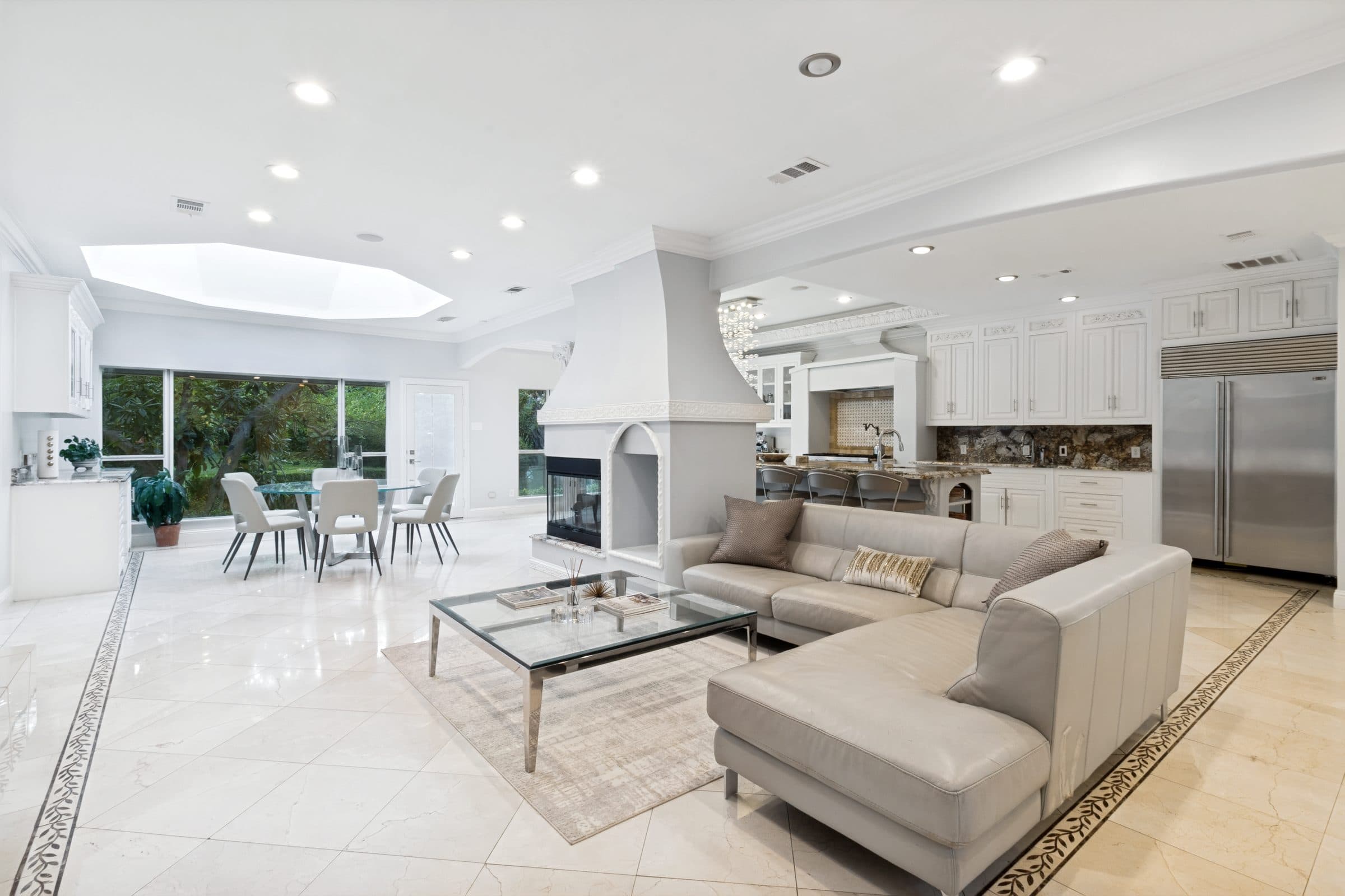 Open-concept great room with fireplace flowing into a white kitchen