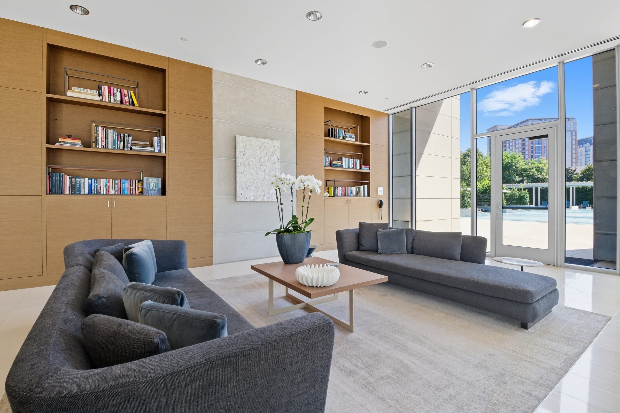 Residential tower lounge with library shelving and pool-view windows